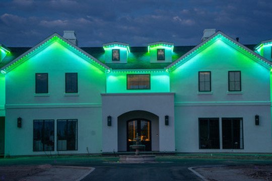 White stucco home with green Bosso Smart Lighting at dusk