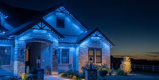 Stone home at sunset with Bosso blue roofline lighting