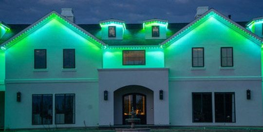 White stucco home with green Bosso Smart Lighting at dusk